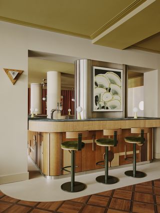 A bar area with cream walls, deep green stools and lime ceiling