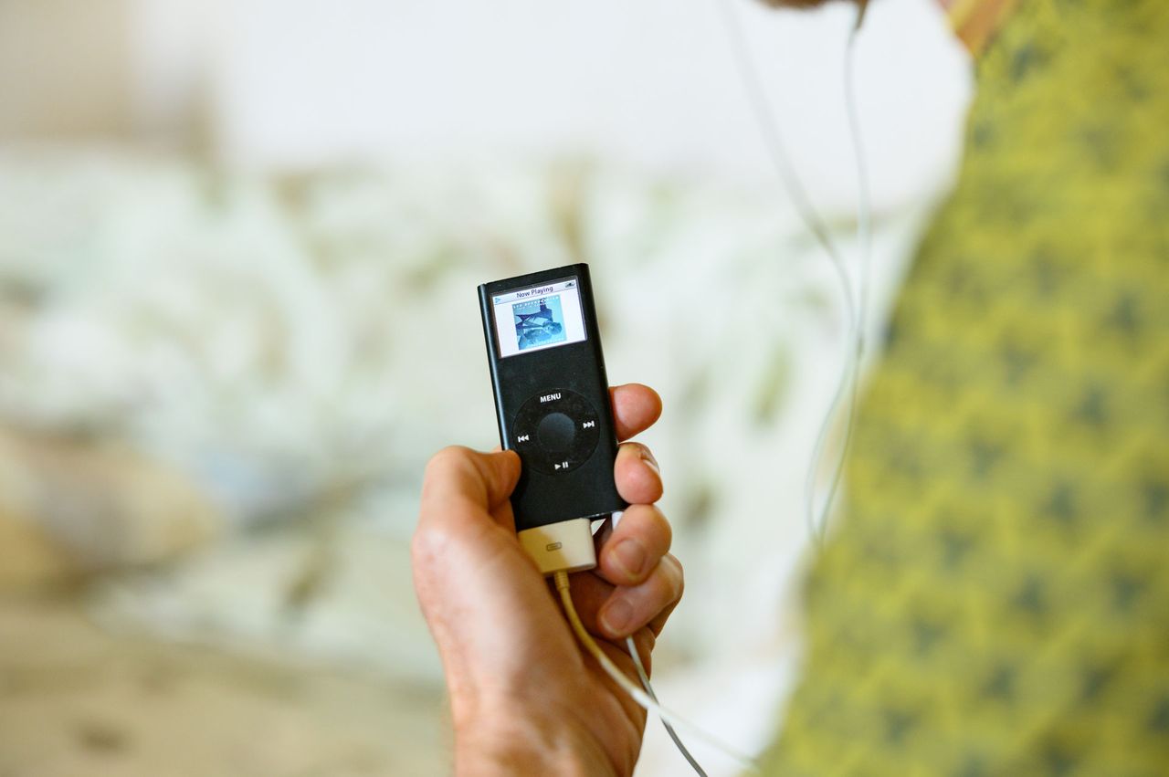 Black iPod Nano 2006 8GB model in person's hand, music artwork on the screen
