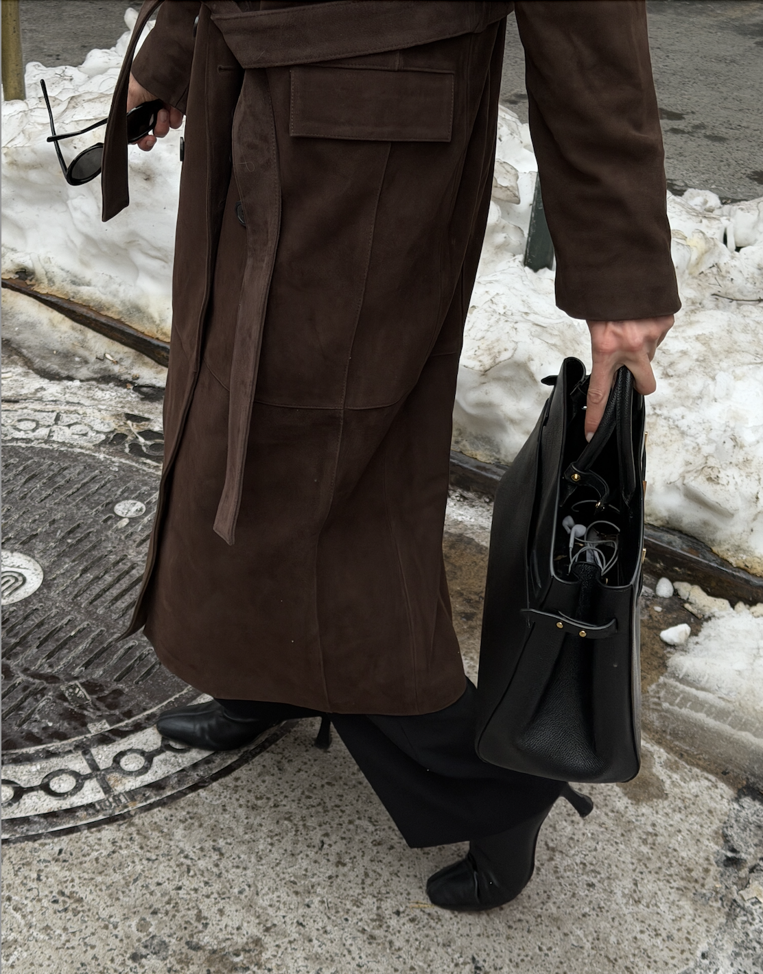 Kathryn Zahorak wearing black hat, brown coat, sunglasses, boots, black bag in new york city
