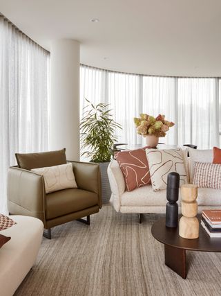 fall autumnal living room with fall cushions, wooden coffee table, armchairs, table in background with flowers