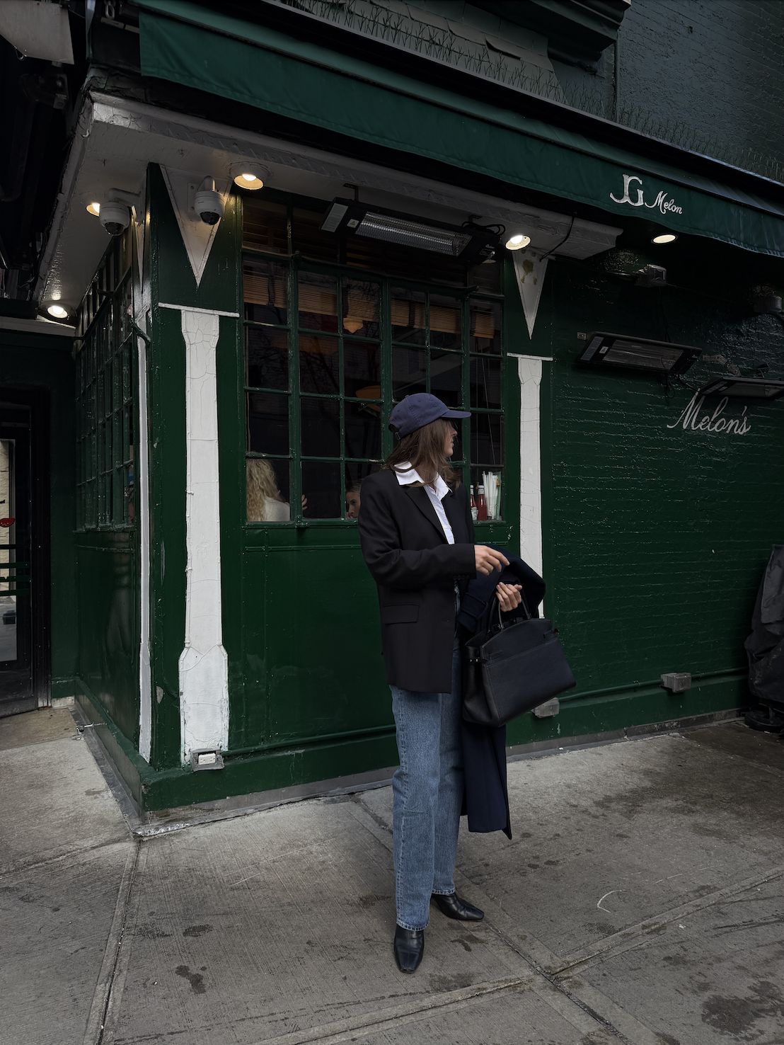 Kathryn Zahorak wearing baseball hat, coat, jeans, boots, black bag in new york city