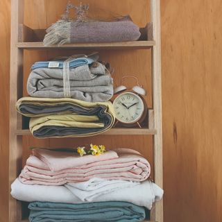 Open shelving with stacks of linens and flowers on them.