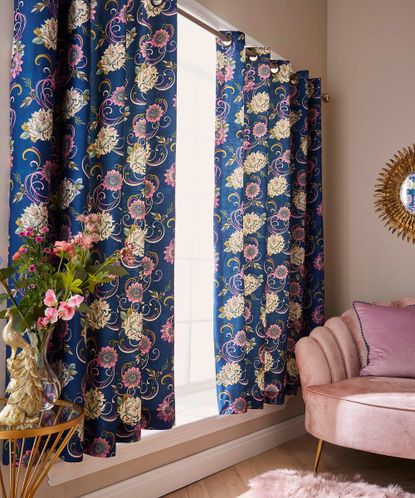 Blue and pink floral floor length curtains in living room with plush light pink velour armchair