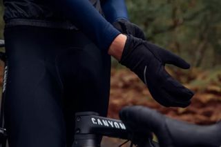 Image shows a rider wearing gloves while cycling in the rain.