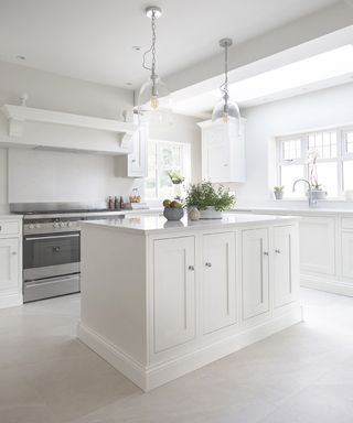 Small white kitchen ideas with white cupboards and island, and a neutral stone floor