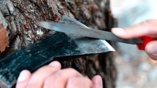 Close up of axe being sharpened with metal file