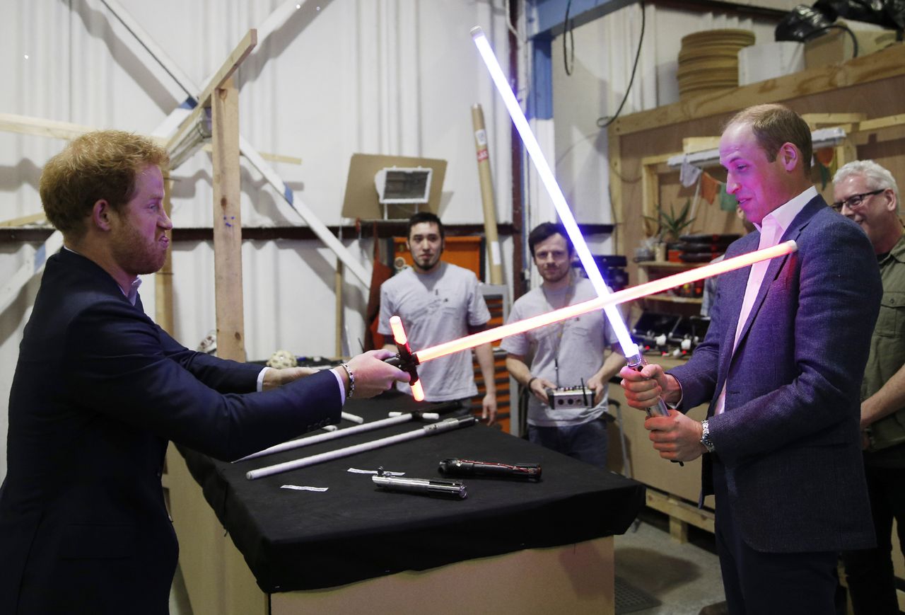 Princes Harry and William try out lightsabers during a tour of the Star Wars sets at Pinewood Studios, Buckinghamshire
