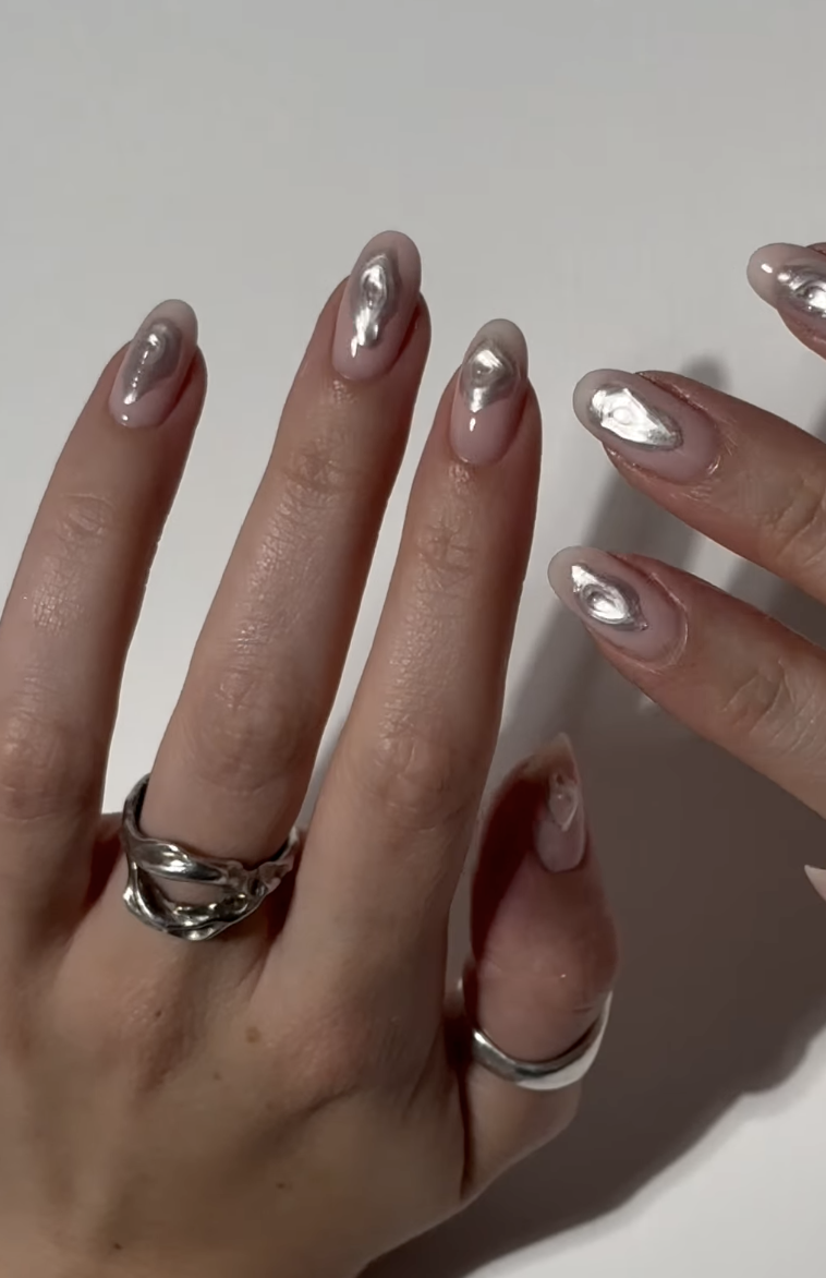 Almond-shaped sheer pink nails decorated with abstract raised shapes in silver chrome