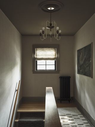 A colour drenched entryway in grey with a small window at the end