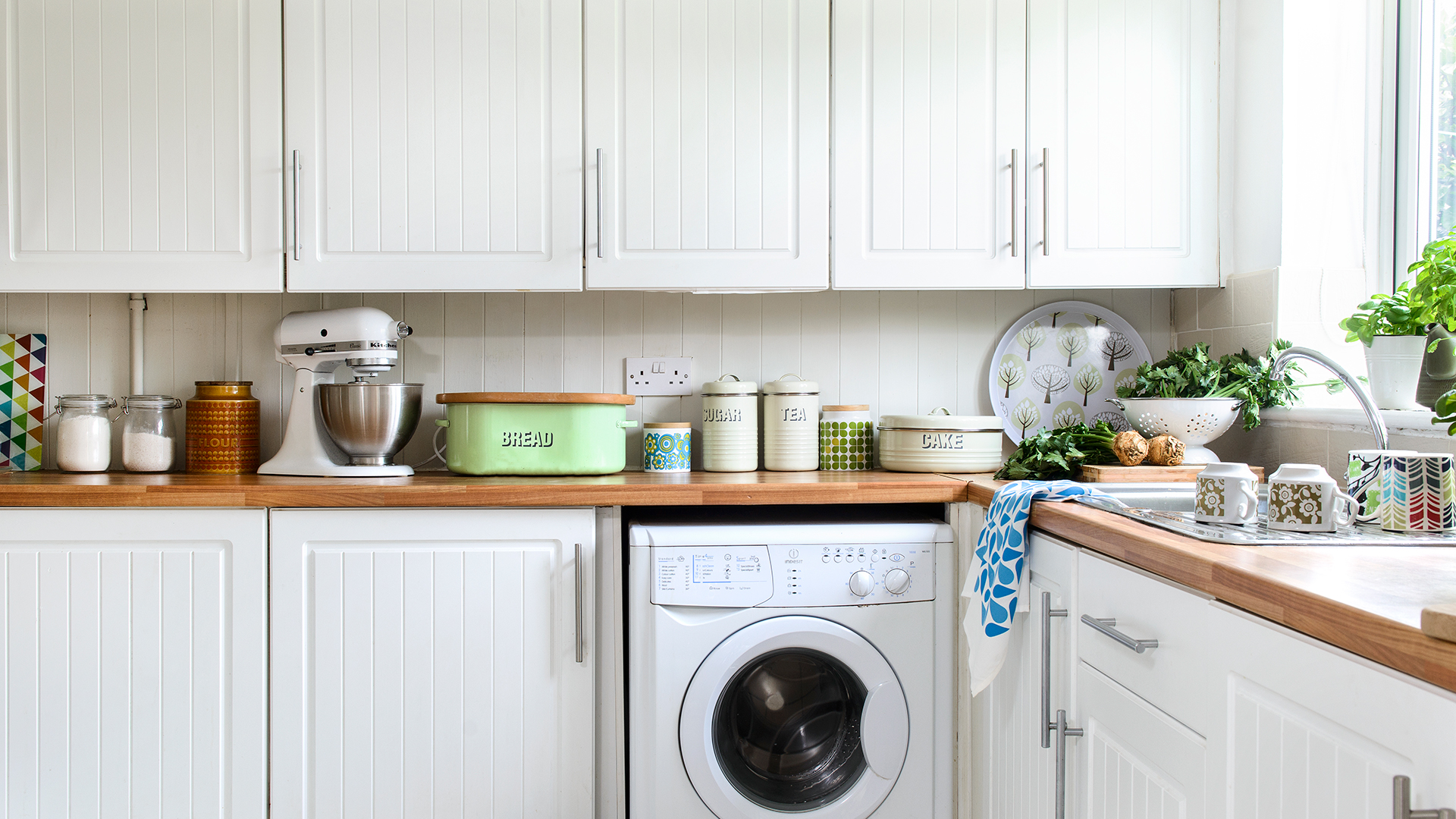 White kitchen with wooden worktops cluttered with kitchen accessories