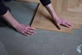 Hands pictured laying a parquet floor