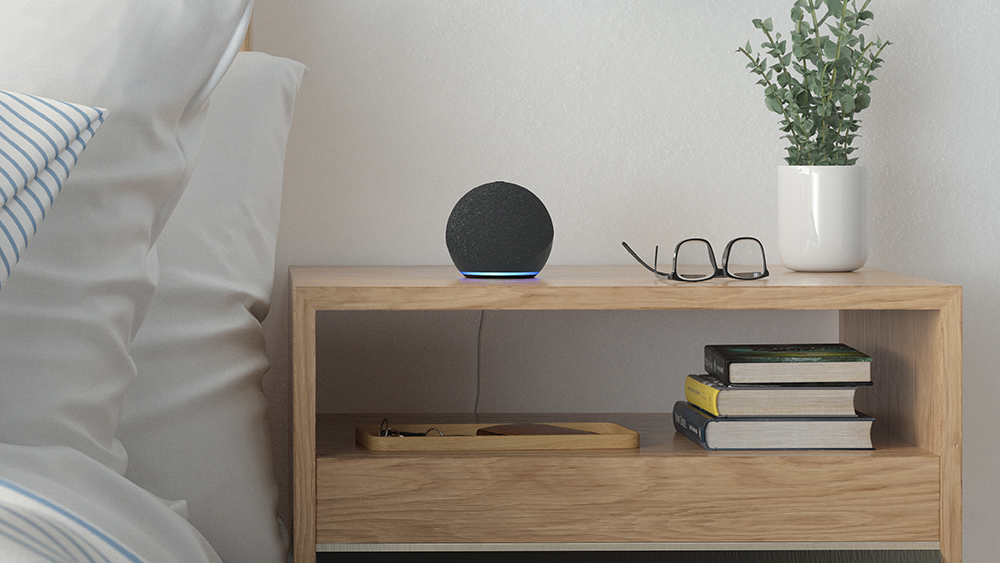 The Amazon Echo Dot in black on a bedside table