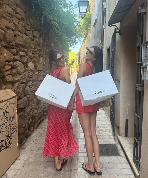Kendall Jenner wearing a red mini dress with The Row flip-flops and carrying The Row's barn tote bag in mesh