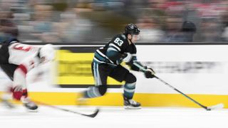 The San Jose Sharks move fast on a breakaway with a blurred background. 