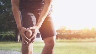 A runner holds his knee in pain