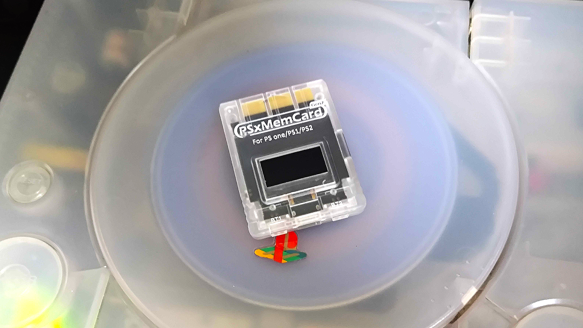 PSxMemCard sitting on top of transparent original PS1 console.