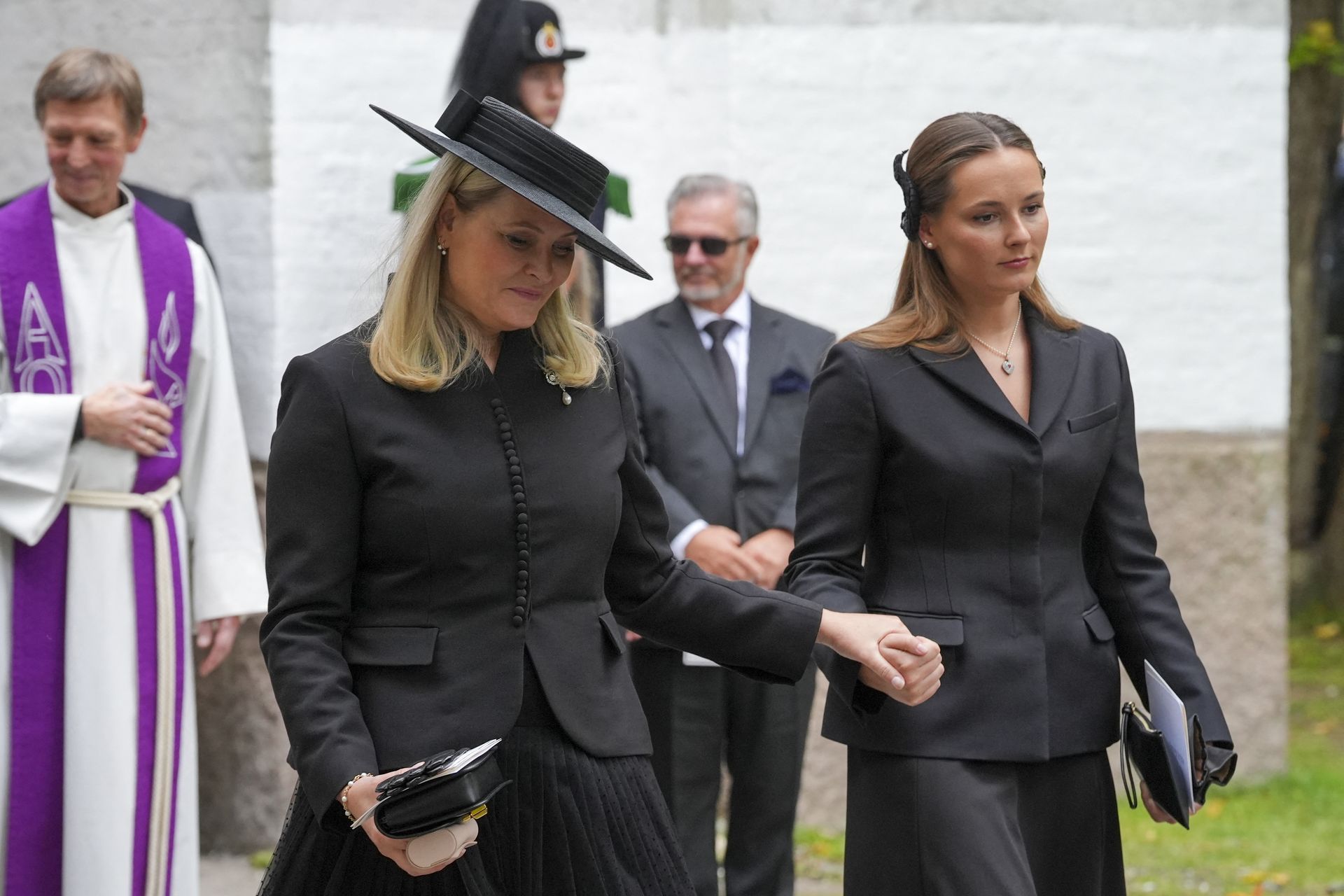 Queen Mette-Marit holding hands with Crown Princess Ingrid-Alexandra at Princess Astrid's funeral