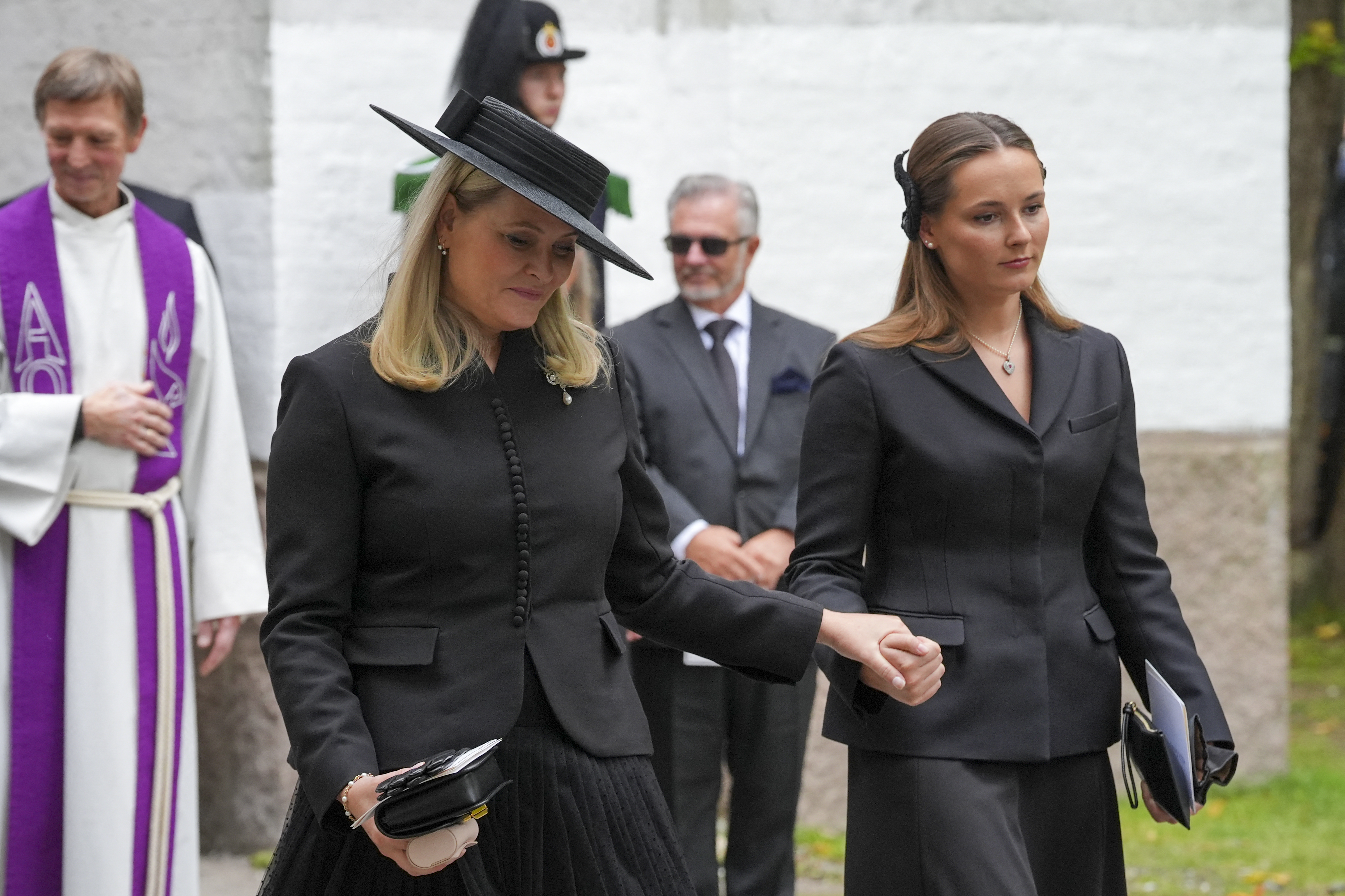 Queen Mette-Marit holding hands with Crown Princess Ingrid-Alexandra at Princess Astrid's funeral