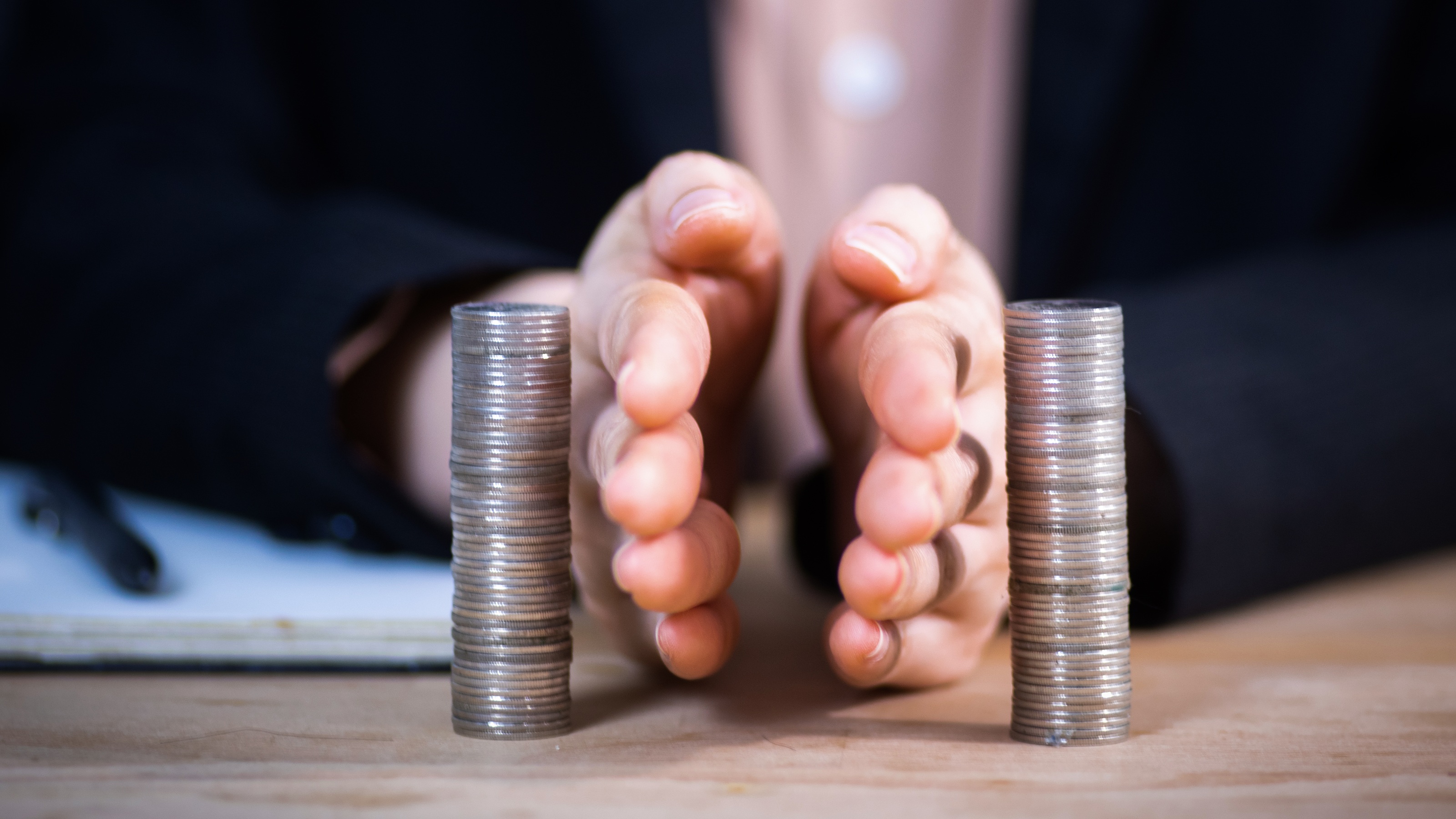 A man puts his hands between two stacks of coins as if to separate them.