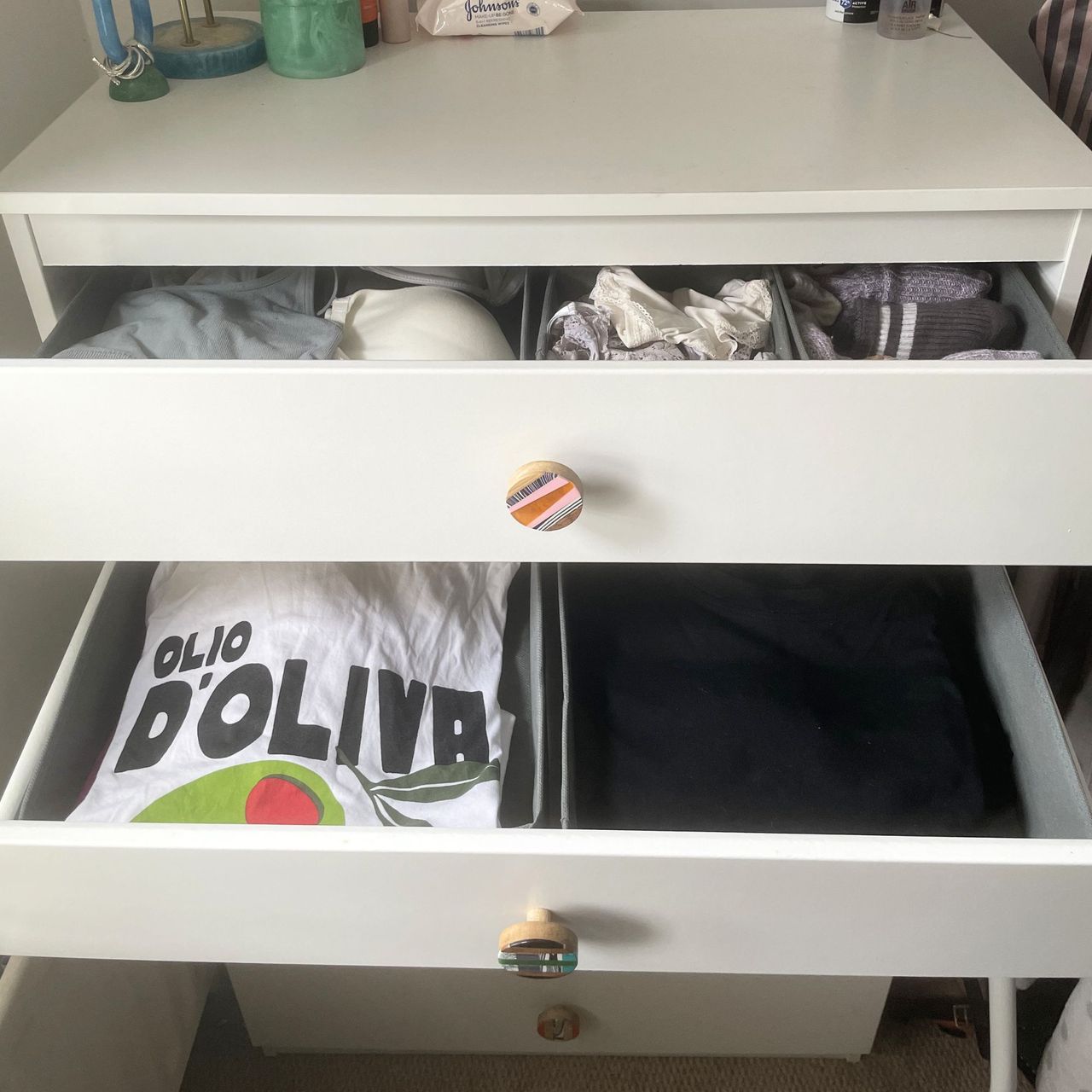 White chest of drawers with the top and middle drawers open, showing clothes organisers inside