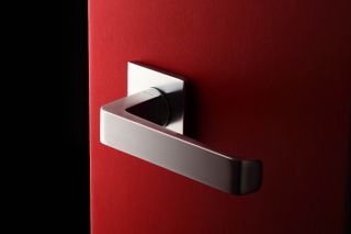 Door handle by Antonio Citterio for Olivari in steel mounted on a red door