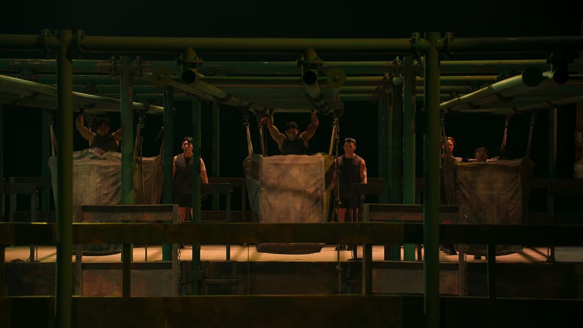 Contestants on the monkey bars preparing to kick huge hanging sandbags in Quest 3 in Physical: 100 season 2 episode 7