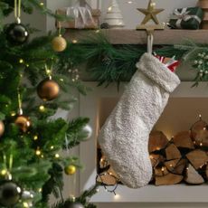 Cream boucle stocking hanging on festive fireplace