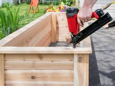 Person Nailing Wooden Box In Garden