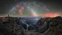 Person stands on rocky cliffs overlooking a calm sea under a vibrant, star-filled night sky with colorful nebulae and galaxy arches