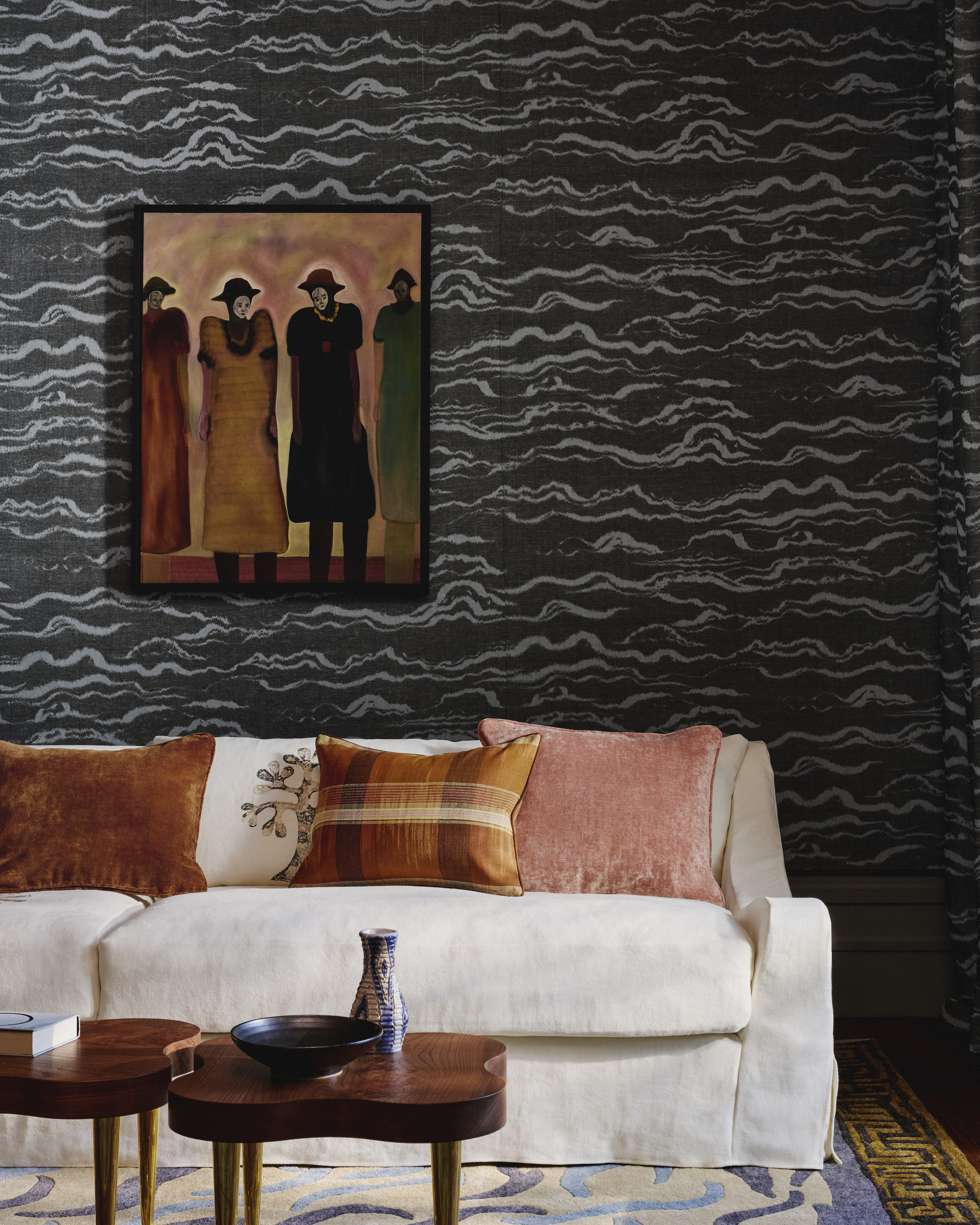 Cream sofa with velvet cushions and a dark patterned wallpaper