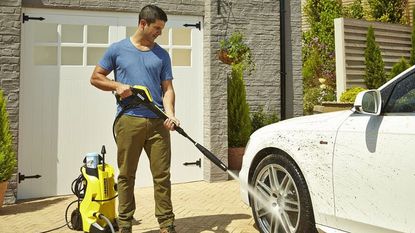 A man cleaning a car with a pressure washer – just one of the best car cleaning products in our list