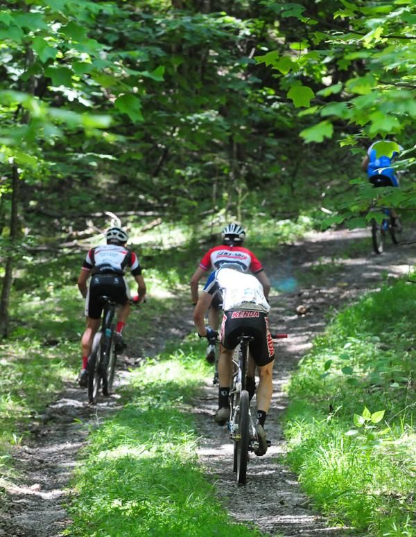Riders climb a shady fireroad.