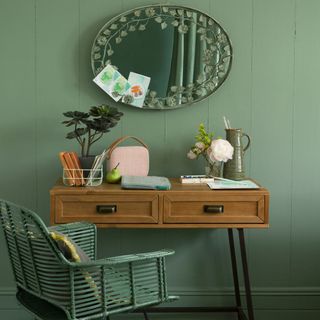 green wall with mirror on wall and table with chair