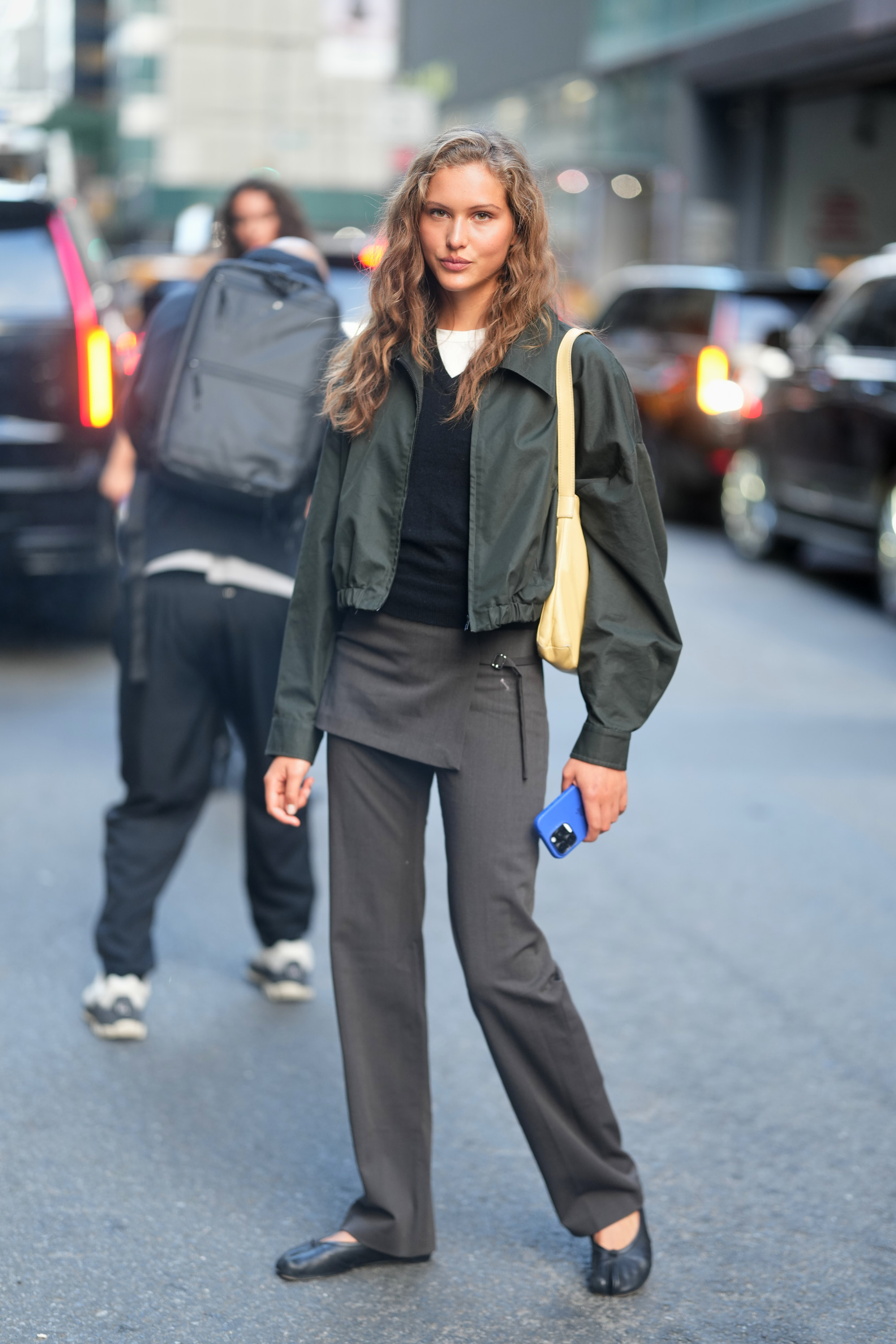 Woman in V-neck sweater, jacket, and skirt pants.