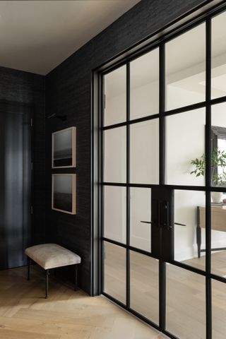 A hallway with charcoal walls and a glass door with a black metal frame