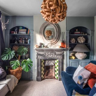 Blue period living room with cast-iron fireplace, built-in display shelves and blue velvet sofa