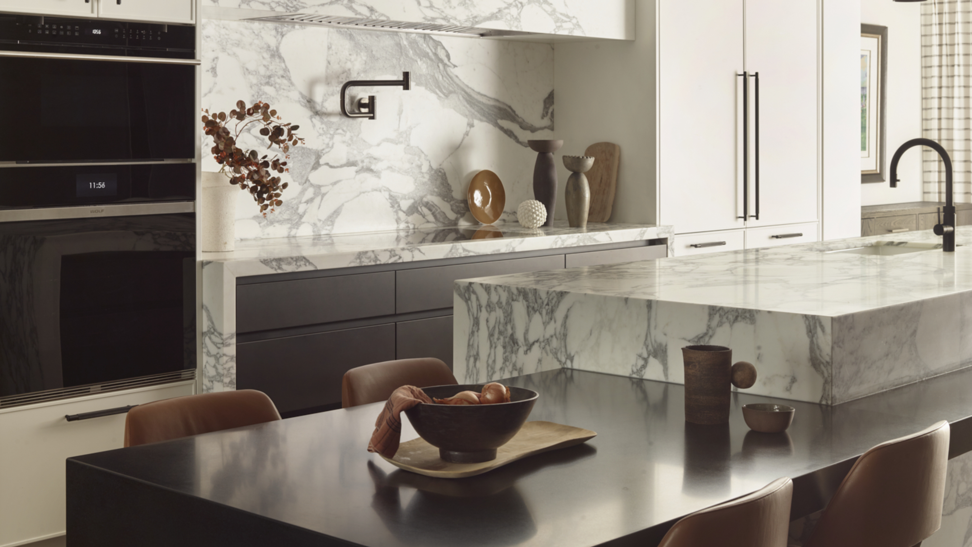 modern kitchen with marble island and attached seating area, and tall cabinets 