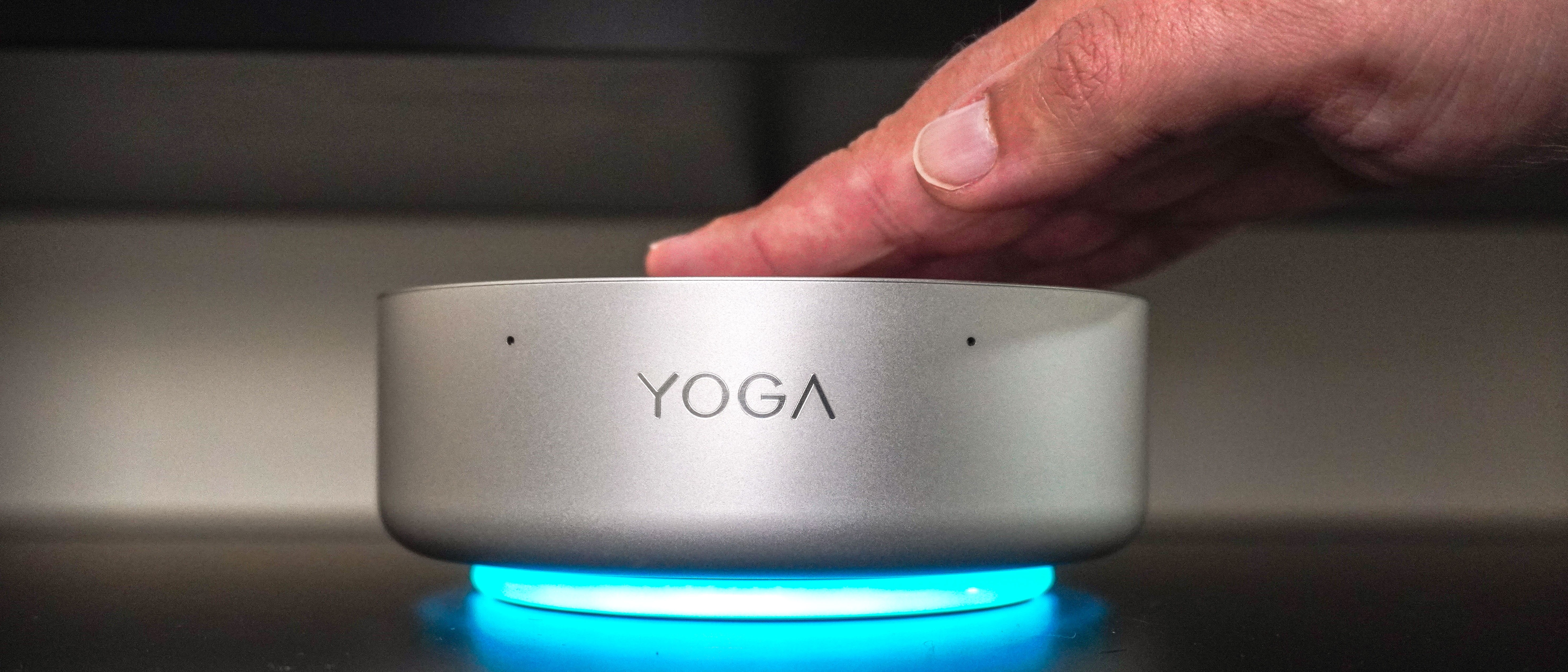A person tapping the top of the Lenovo Yoga Mini mini PC