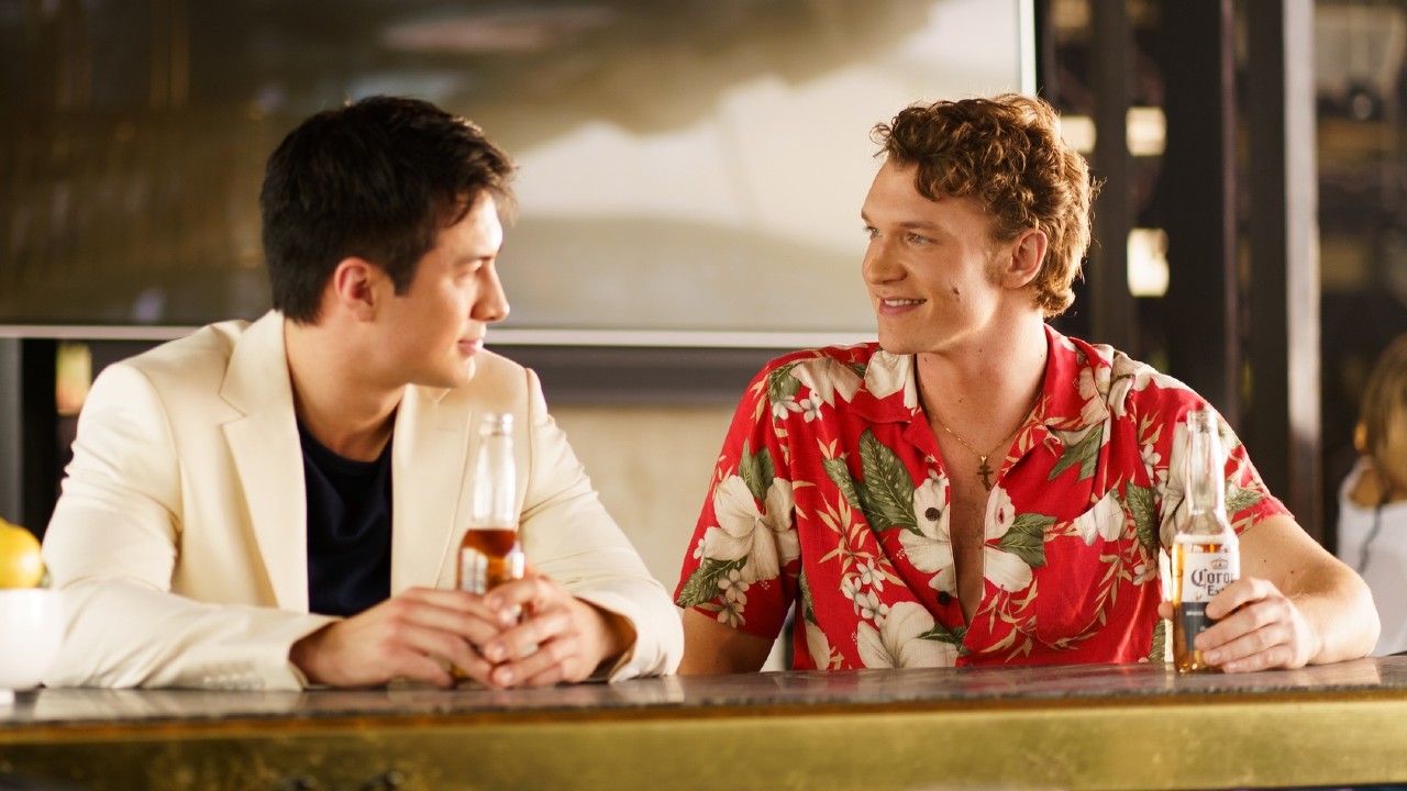 From left to right: Shane holding a beer and looking at Ilya who is looking back at him. They're both sitting at a bar.