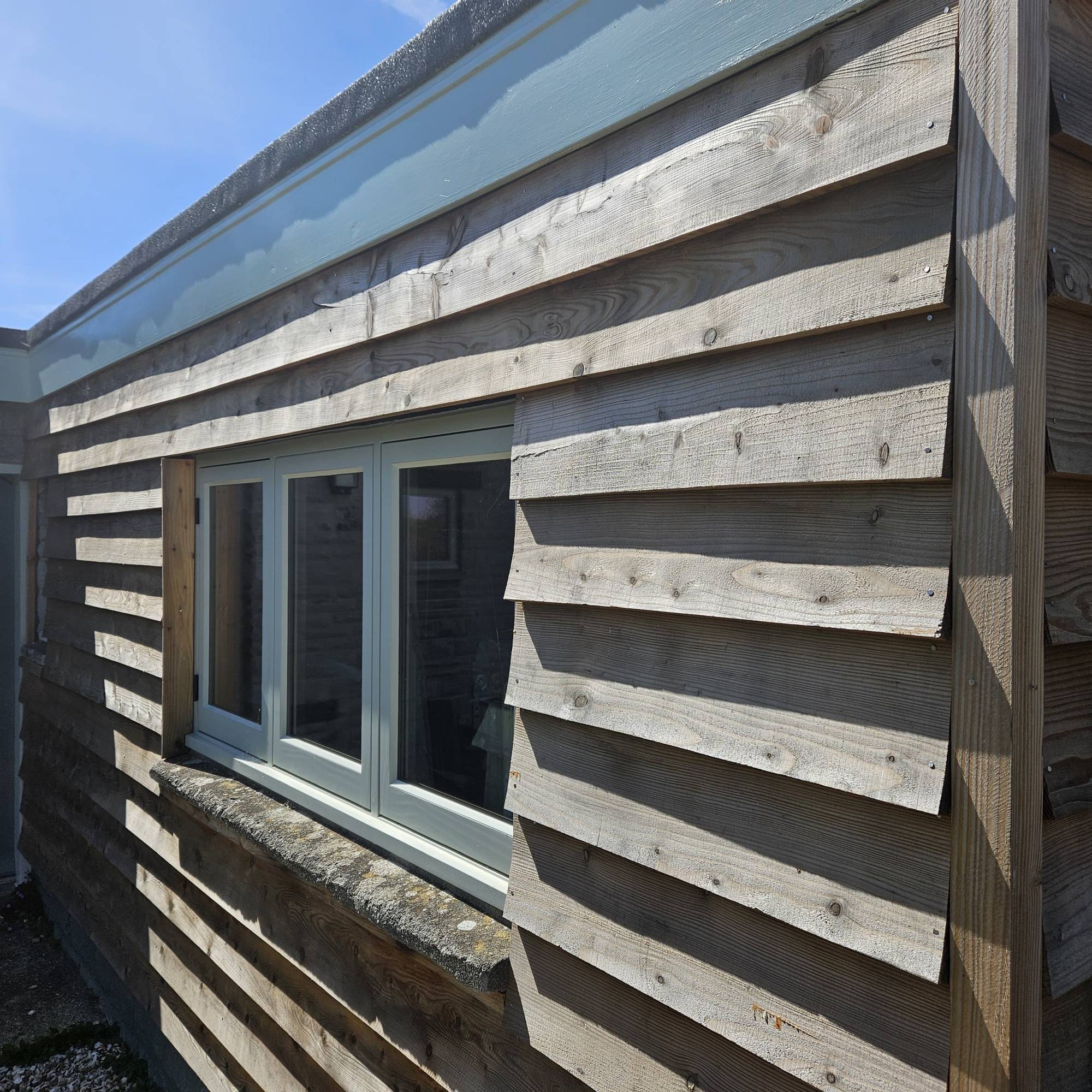 Shiplap timber cladding on garage with light blue window