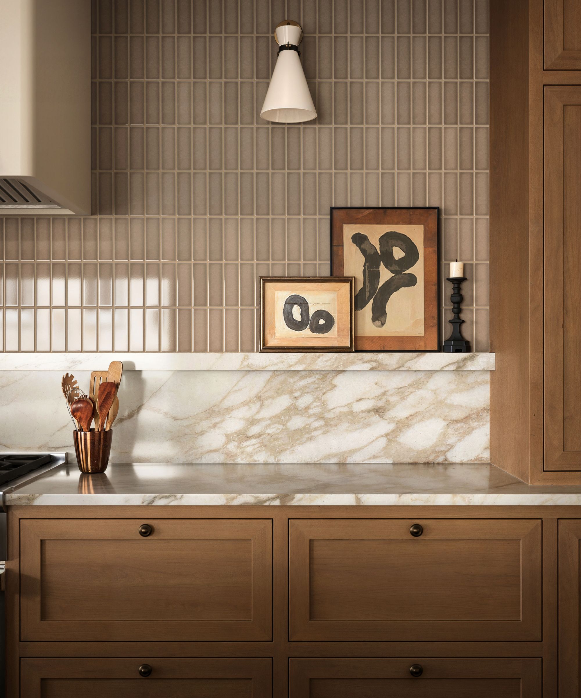 A wooden kitchen with a marble countersplash and warm neutral glossy wall tiles