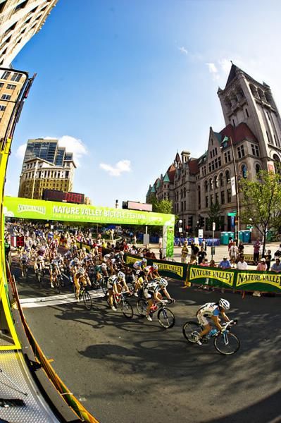 The women's field passes through the start finish with the Saint Paul Landmark center in the background.