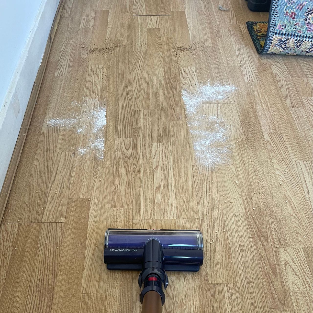 Dyson Gen5detect on hardwood floor next to cous cous, flour and sugar, and coffee grounds