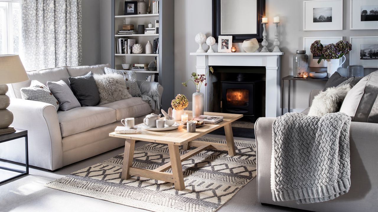 Grey living with lit fire, cosy knits and a wooden coffee table