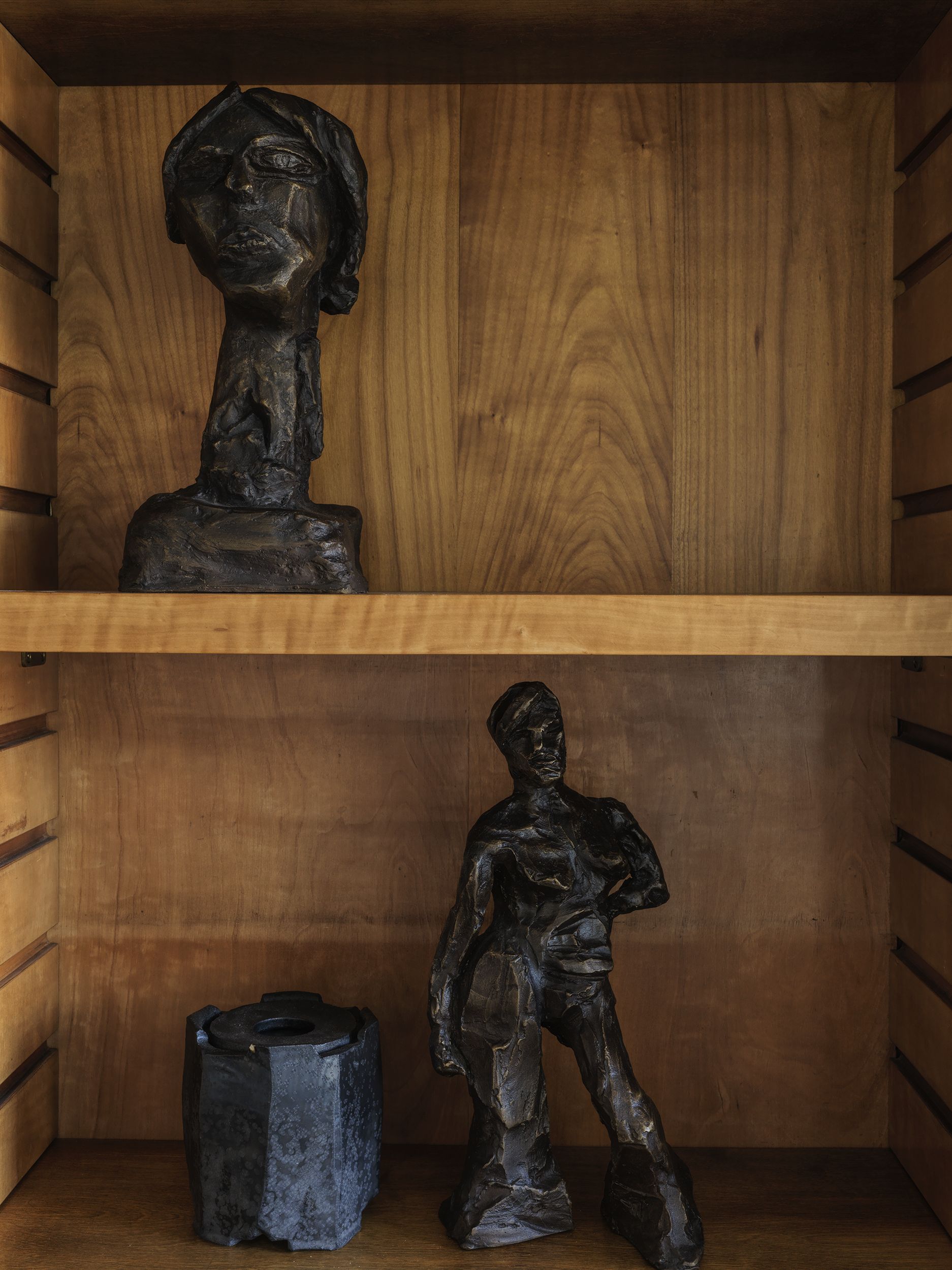 A wood shelving unit with black scuptures on the shelves