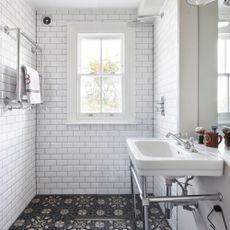 metro bathroom with black and white floor tiles with floral pattern white wall tiles shower and basin with chrome wash stand