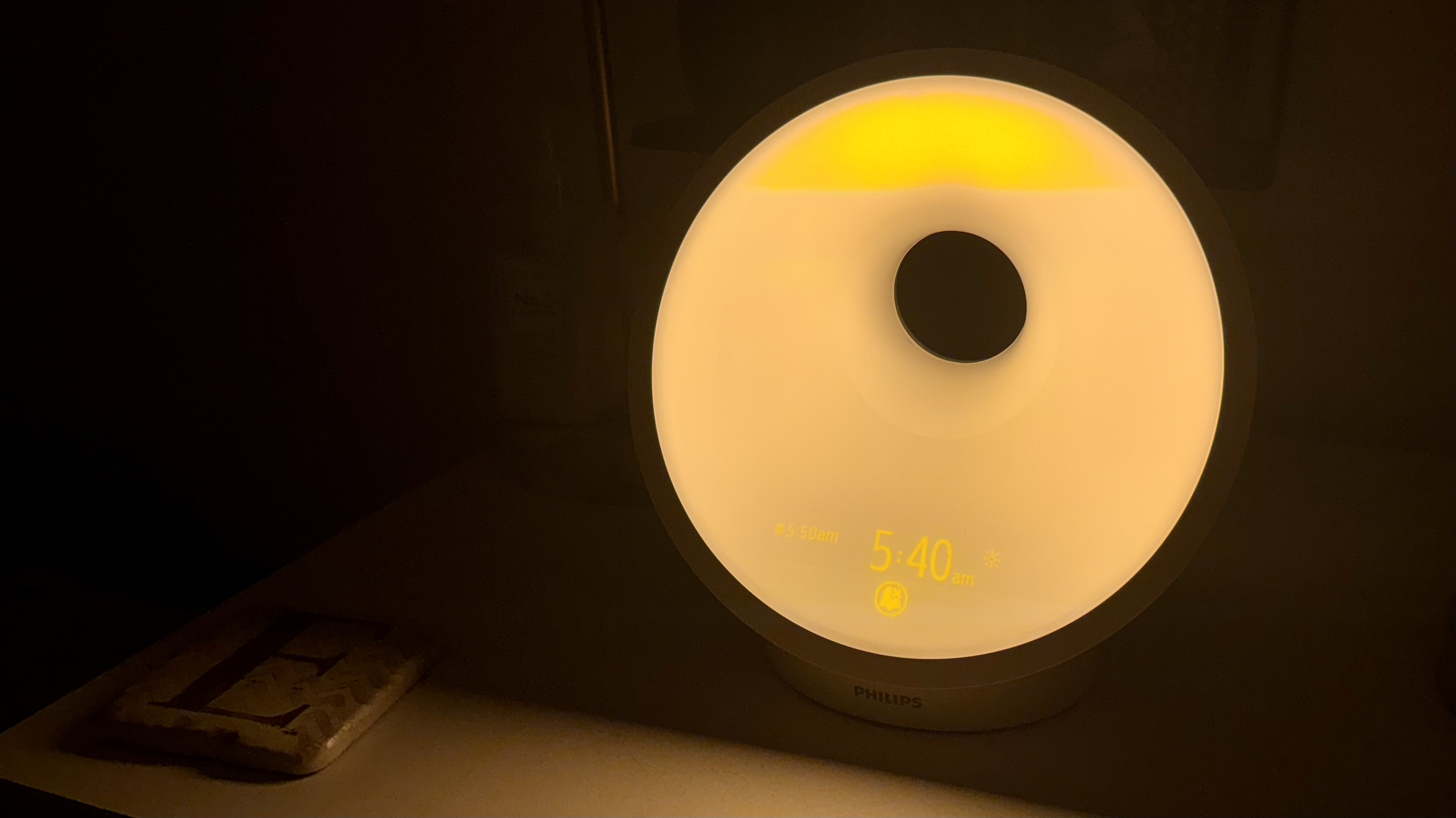 Philips SmartSleep HF3651 wake-up light on bedside on sunrise function with warm yellow light..