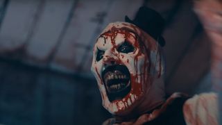 David Howard Thornton smiles while splattered with blood in Terrifier 2.