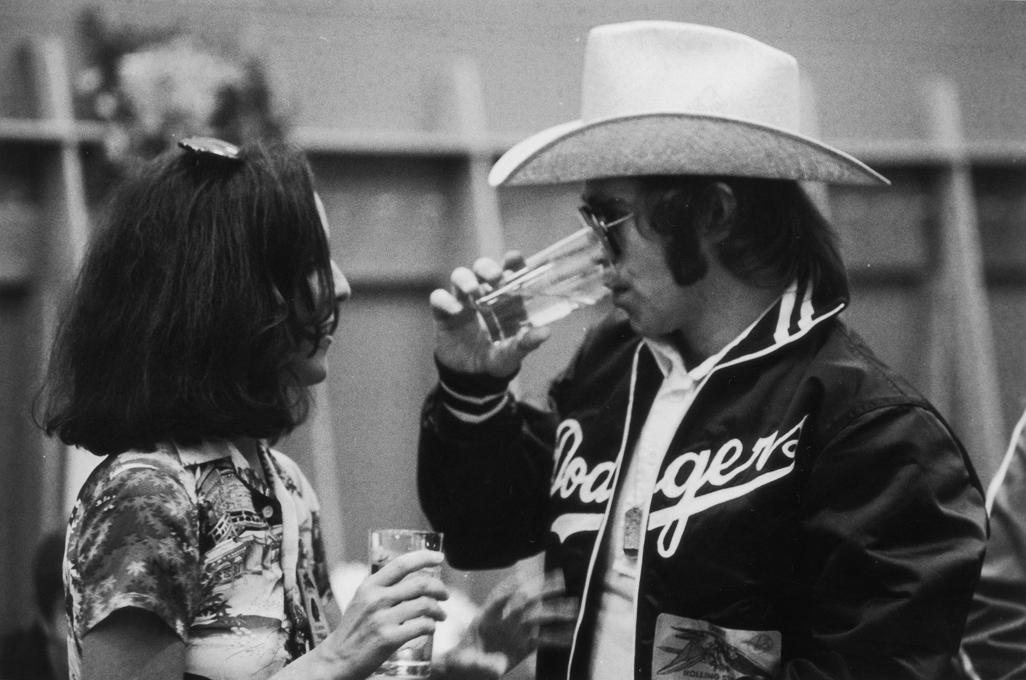 Music journalist Lisa Robinson chats to British pop star Elton John backstage at a concert on the the Rolling Stones' 1975 Tour of the Americas.
