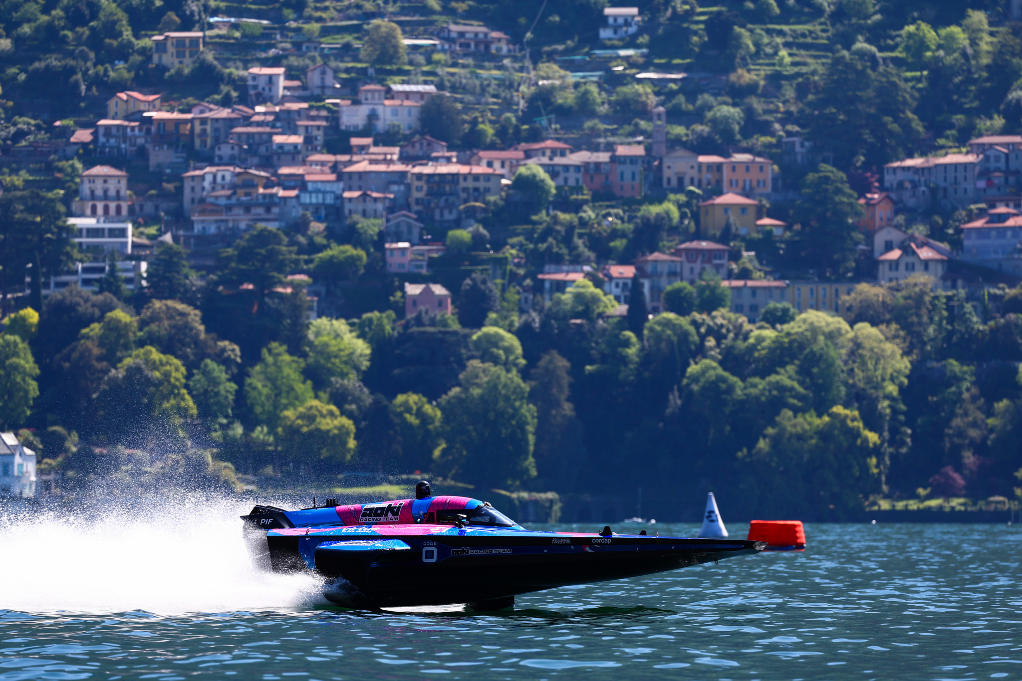A powerboat speeding along the waters of Lake Como, with italian villas in the background.